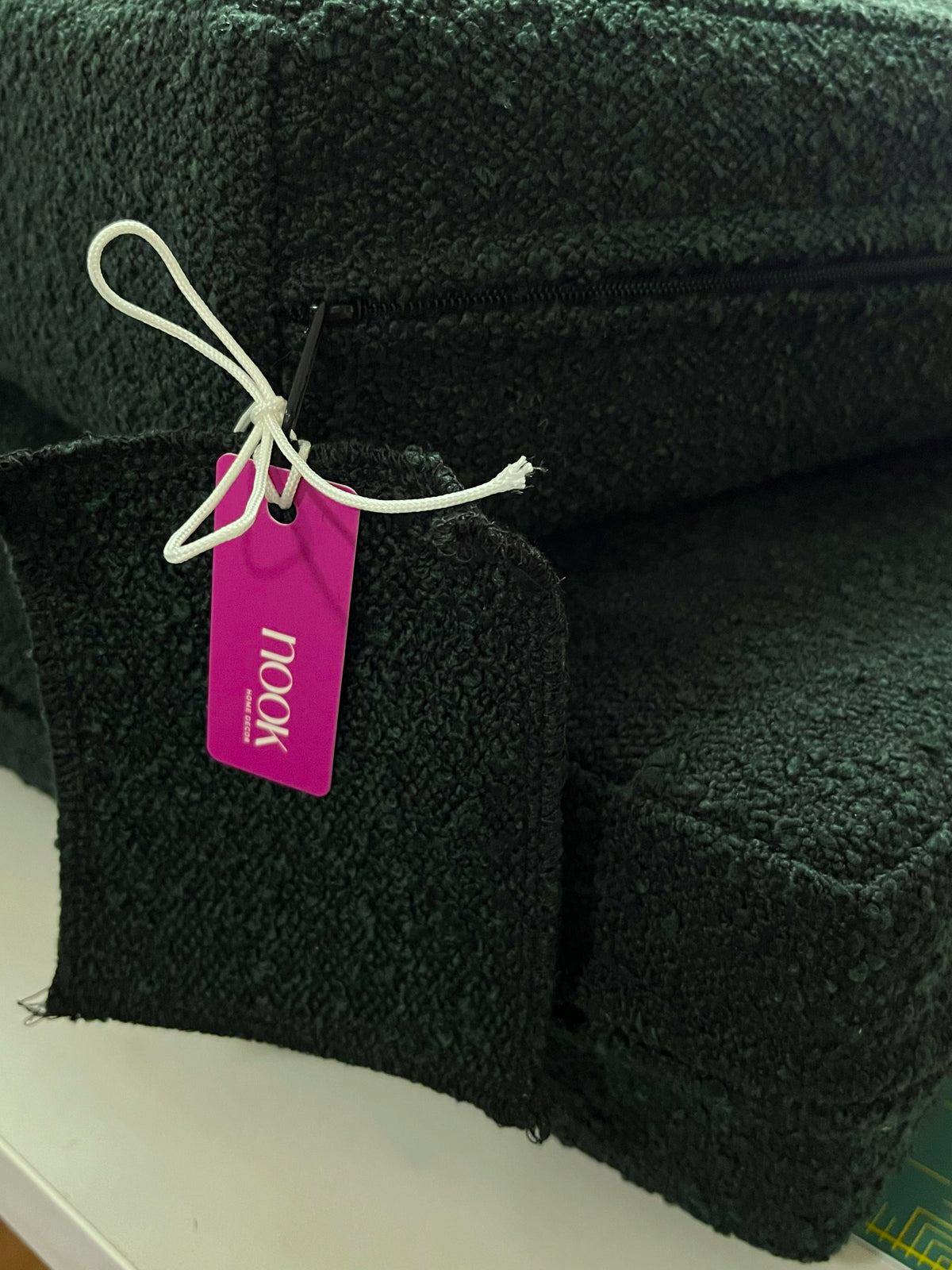 Close-up of a dark forest green plush or fleece upholstered furniture piece, showing a zipper, textured fabric.